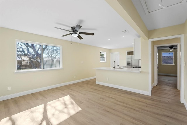 unfurnished living room with ceiling fan, sink, and light wood-type flooring