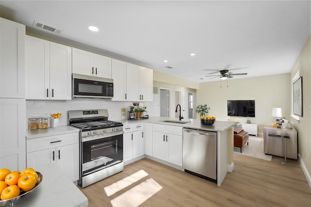 kitchen with sink, white cabinetry, kitchen peninsula, and appliances with stainless steel finishes