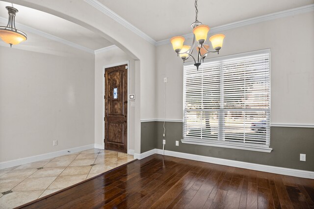 spare room featuring hardwood / wood-style flooring, a notable chandelier, a healthy amount of sunlight, and ornamental molding