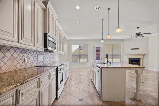 kitchen with sink, crown molding, decorative light fixtures, appliances with stainless steel finishes, and an island with sink