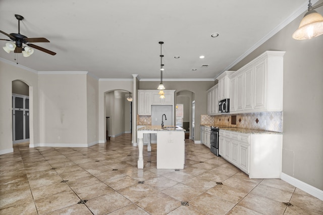 kitchen featuring light stone counters, a center island with sink, appliances with stainless steel finishes, pendant lighting, and white cabinets