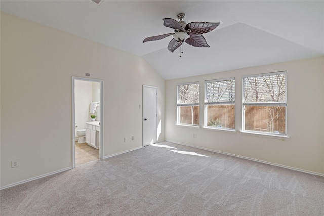 unfurnished bedroom with ceiling fan, ensuite bathroom, light colored carpet, vaulted ceiling, and a closet