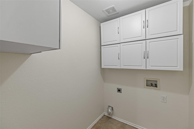 laundry room with electric dryer hookup, cabinets, light tile patterned floors, and hookup for a washing machine