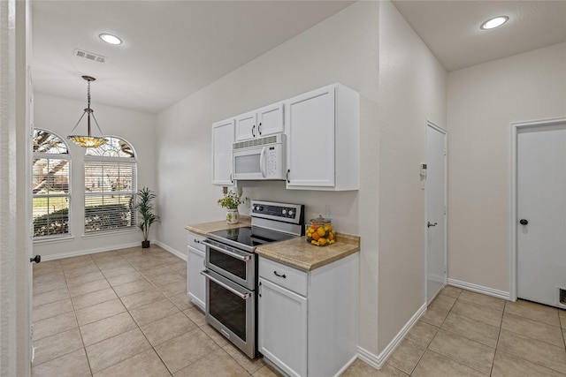 kitchen with white cabinets, decorative light fixtures, range with two ovens, and light tile patterned flooring