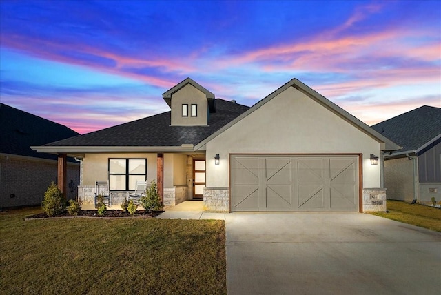 view of front of home featuring an attached garage, stucco siding, concrete driveway, a front lawn, and stone siding