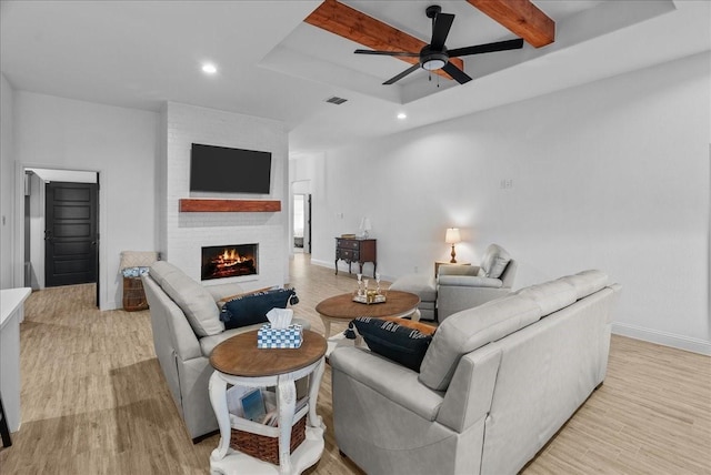 living room featuring light wood finished floors, baseboards, a large fireplace, and ceiling fan