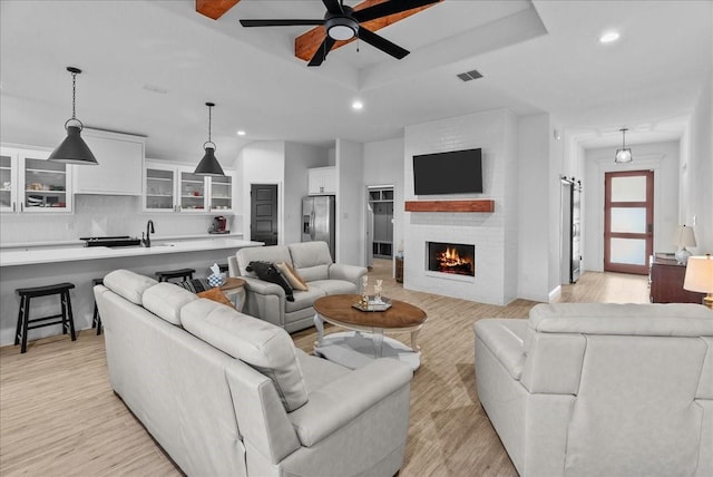 living room with light wood finished floors, recessed lighting, a raised ceiling, and a ceiling fan