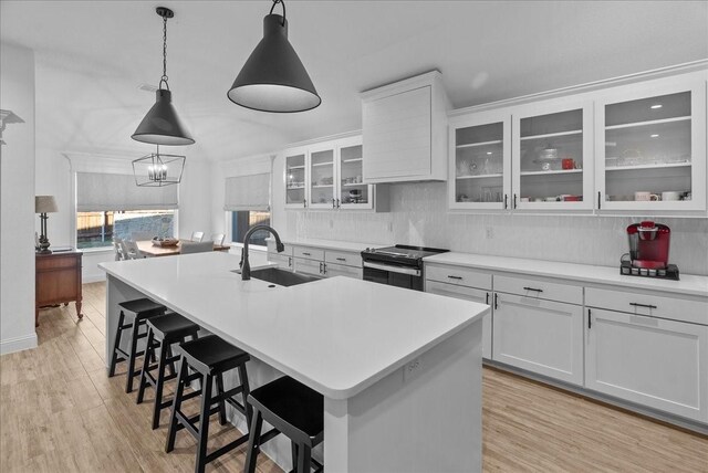 kitchen with a breakfast bar, light wood-style flooring, a kitchen island with sink, electric range oven, and a sink