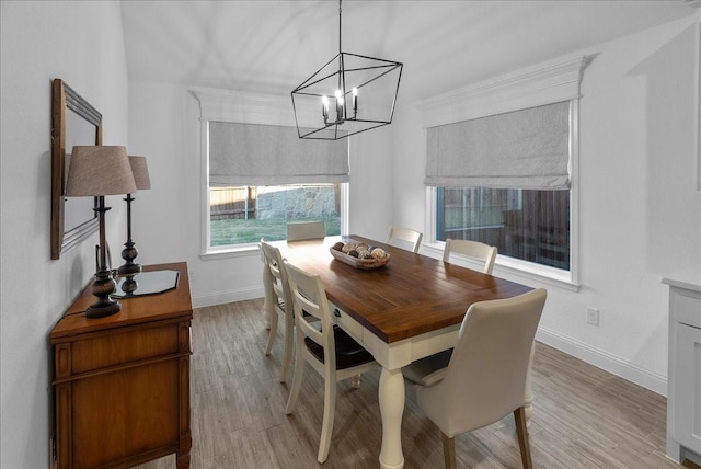 dining space featuring baseboards, a notable chandelier, and light wood-style flooring