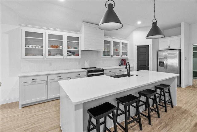 kitchen with an island with sink, light wood-style floors, appliances with stainless steel finishes, and a sink