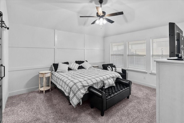 bedroom featuring carpet, baseboards, ceiling fan, vaulted ceiling, and a decorative wall