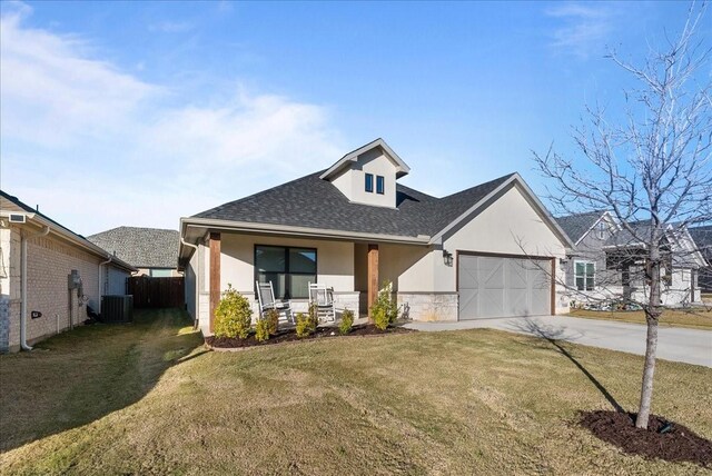 view of front of house featuring central AC unit, a porch, a garage, and a front yard