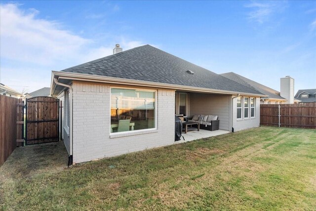 rear view of house featuring brick siding, a lawn, outdoor lounge area, and a fenced backyard