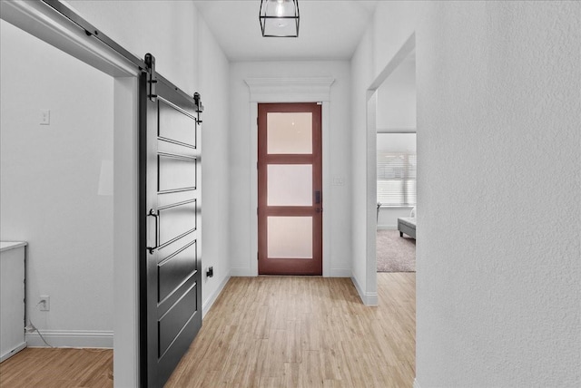 entryway with light wood-style flooring, baseboards, and a barn door