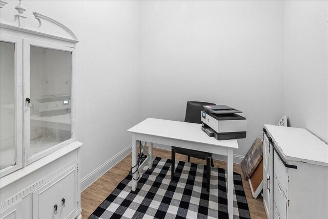 office area with baseboards and light wood finished floors