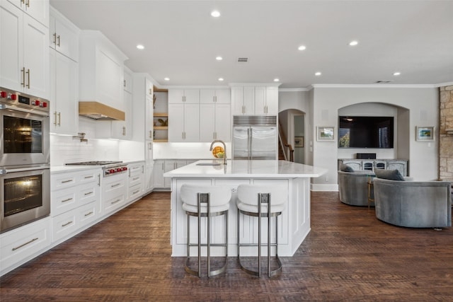 kitchen featuring white cabinets, stainless steel appliances, and a center island with sink