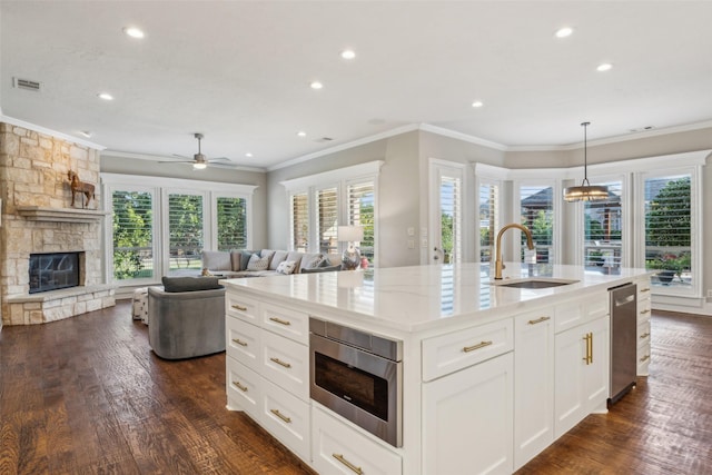 kitchen featuring white cabinetry, sink, dark hardwood / wood-style floors, a kitchen island with sink, and a fireplace