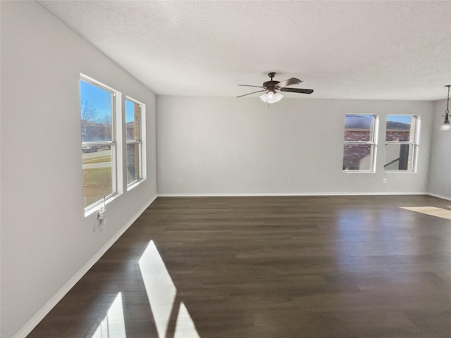 empty room featuring a textured ceiling, dark hardwood / wood-style floors, and plenty of natural light