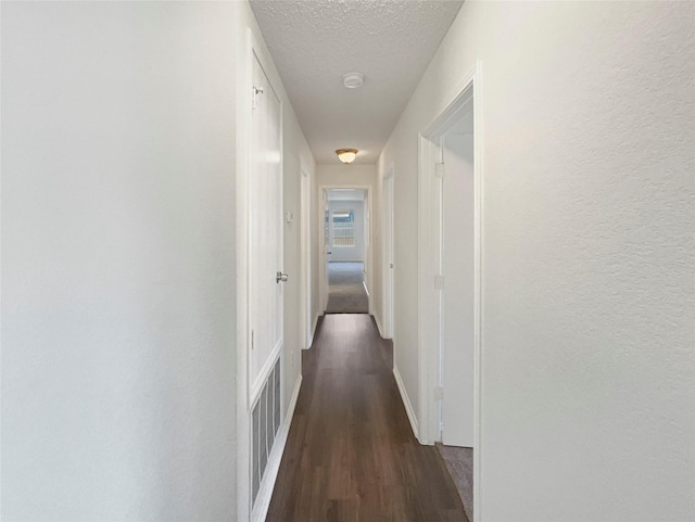 hallway featuring a textured ceiling and dark wood-type flooring