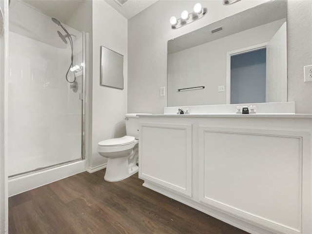 bathroom featuring hardwood / wood-style flooring, vanity, toilet, and walk in shower