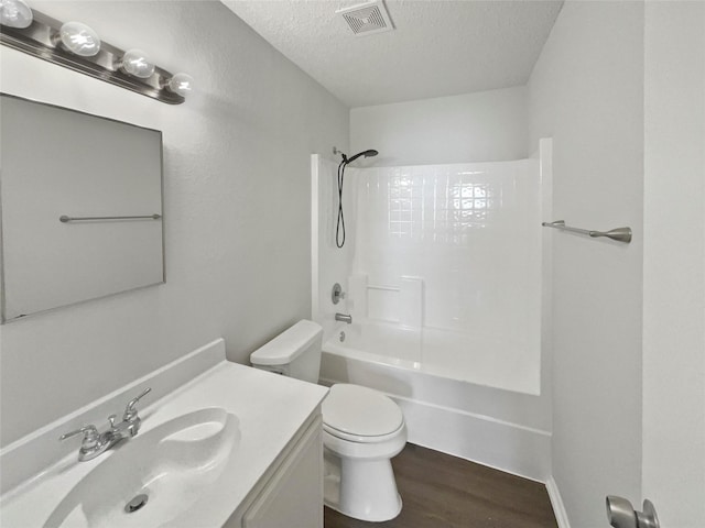 full bathroom featuring vanity, shower / washtub combination, hardwood / wood-style flooring, toilet, and a textured ceiling