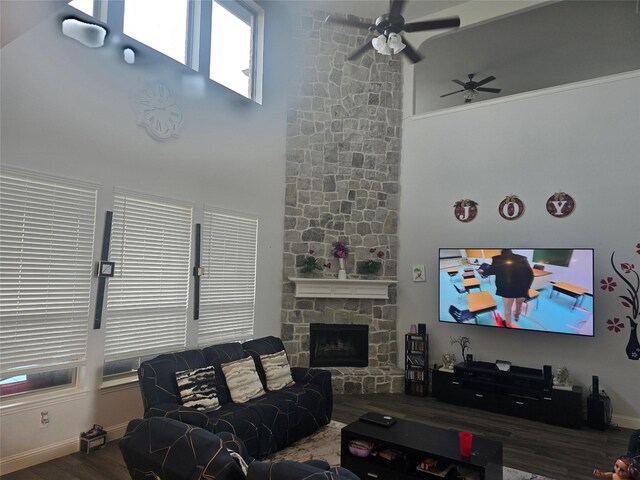 living room featuring ceiling fan, a fireplace, and dark wood-type flooring