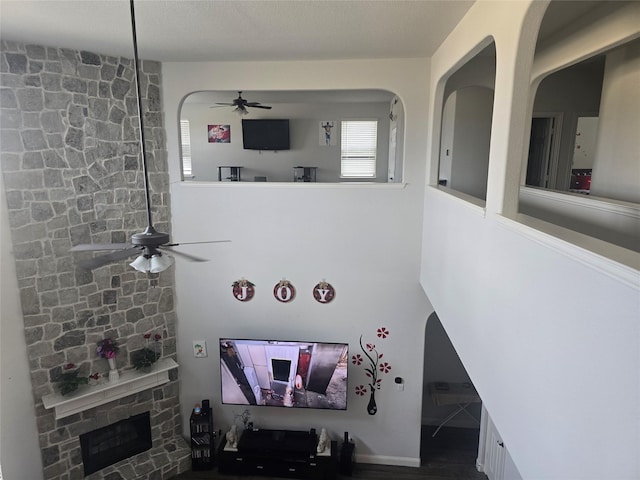 living room featuring ceiling fan and a stone fireplace