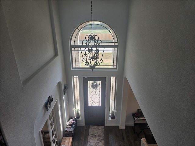 foyer entrance with dark wood-type flooring, a high ceiling, and a chandelier