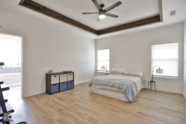 bedroom with a tray ceiling, light hardwood / wood-style flooring, and ceiling fan