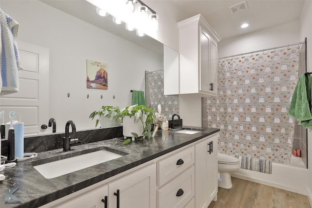 full bathroom featuring hardwood / wood-style floors, vanity, toilet, and shower / bath combo