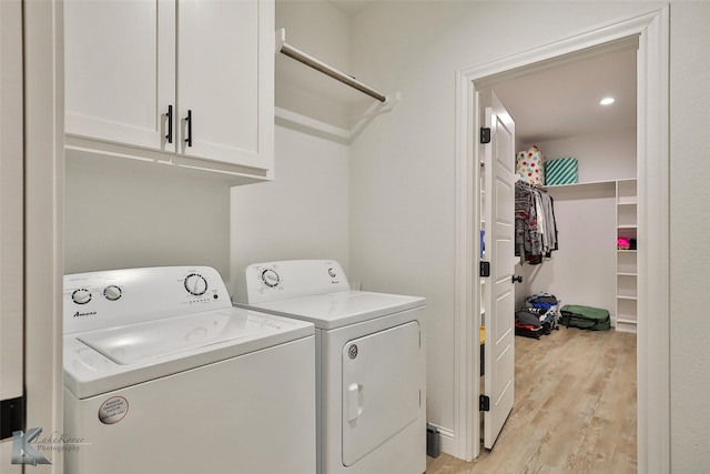 washroom featuring washer and dryer, cabinets, and light wood-type flooring