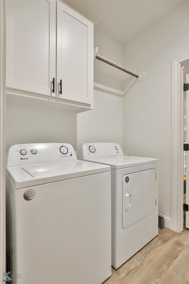 laundry area with cabinets, light hardwood / wood-style floors, and washer and dryer