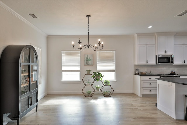 kitchen featuring white cabinets, crown molding, hanging light fixtures, decorative backsplash, and a chandelier