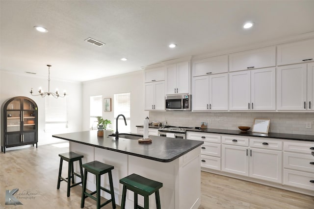 kitchen featuring appliances with stainless steel finishes, sink, a notable chandelier, a breakfast bar area, and an island with sink