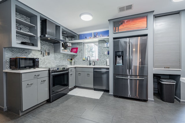 kitchen featuring appliances with stainless steel finishes, tasteful backsplash, gray cabinetry, sink, and wall chimney range hood