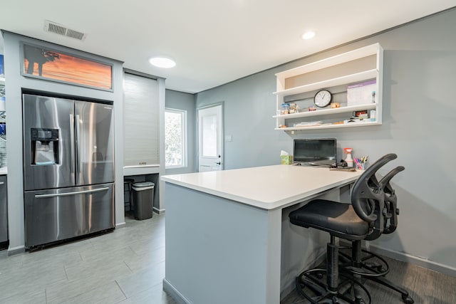 kitchen featuring kitchen peninsula, stainless steel fridge with ice dispenser, and a kitchen breakfast bar