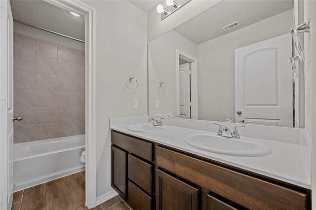 full bathroom with tiled shower / bath, vanity, and toilet