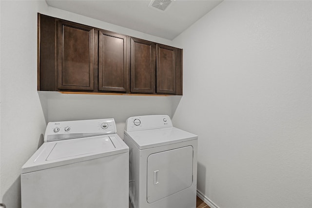 clothes washing area with washer and dryer and cabinets