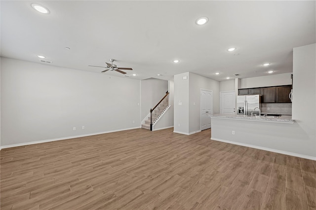 unfurnished living room featuring ceiling fan and light hardwood / wood-style flooring