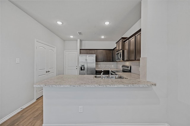 kitchen featuring kitchen peninsula, dark brown cabinets, stainless steel appliances, and sink