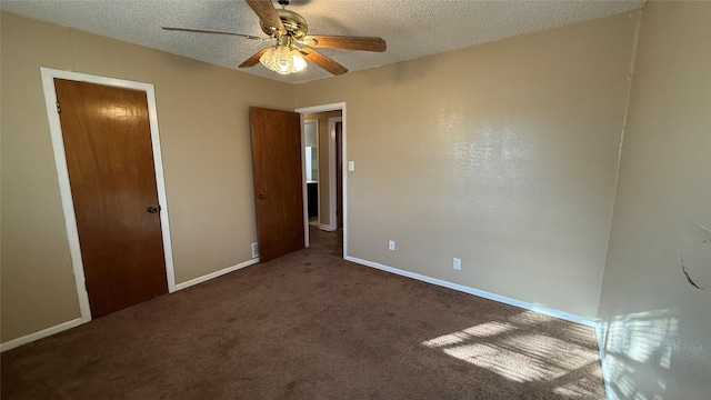 unfurnished bedroom with ceiling fan, dark carpet, and a textured ceiling