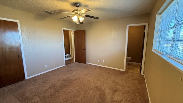 unfurnished bedroom with ceiling fan, carpet flooring, a textured ceiling, and ensuite bath