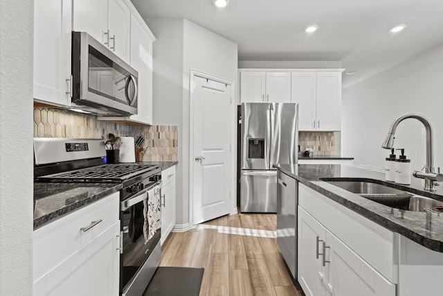 kitchen featuring dark stone countertops, white cabinetry, sink, and appliances with stainless steel finishes