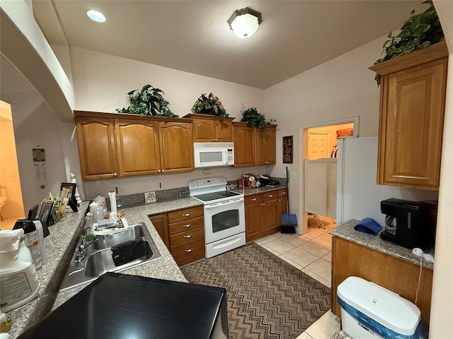 kitchen with light tile patterned flooring, sink, light stone counters, and white appliances