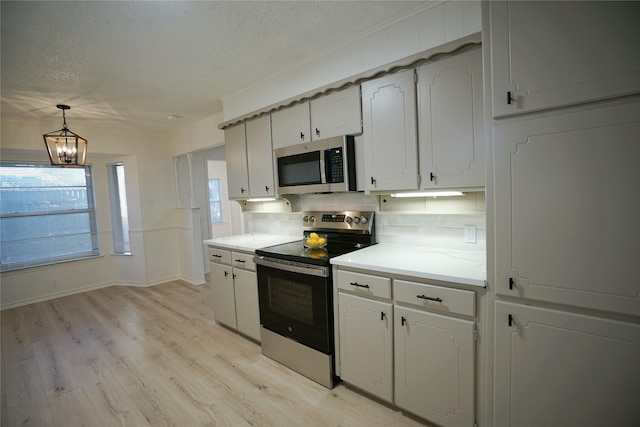 kitchen featuring white cabinetry, backsplash, a chandelier, decorative light fixtures, and appliances with stainless steel finishes