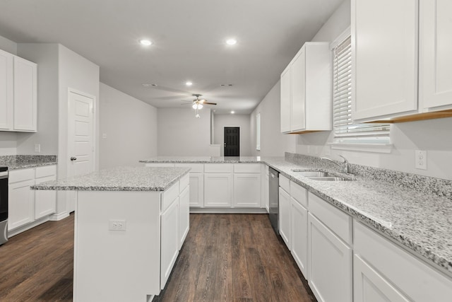 kitchen featuring light stone countertops, a center island, sink, and white cabinets