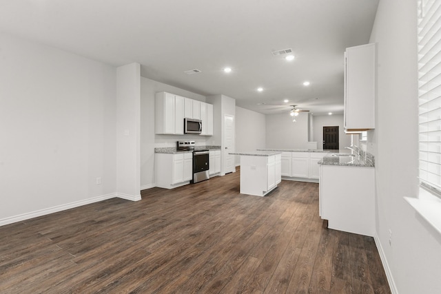 kitchen featuring light stone countertops, stainless steel appliances, kitchen peninsula, and white cabinets