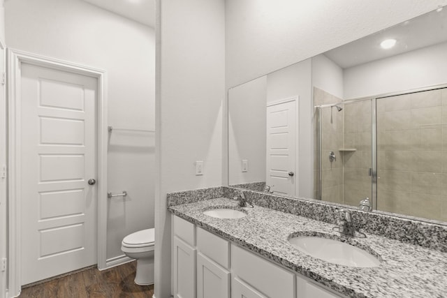 bathroom with vanity, hardwood / wood-style flooring, a shower with door, and toilet