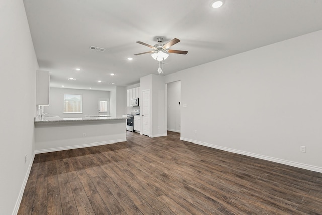 unfurnished living room featuring dark wood-type flooring and ceiling fan