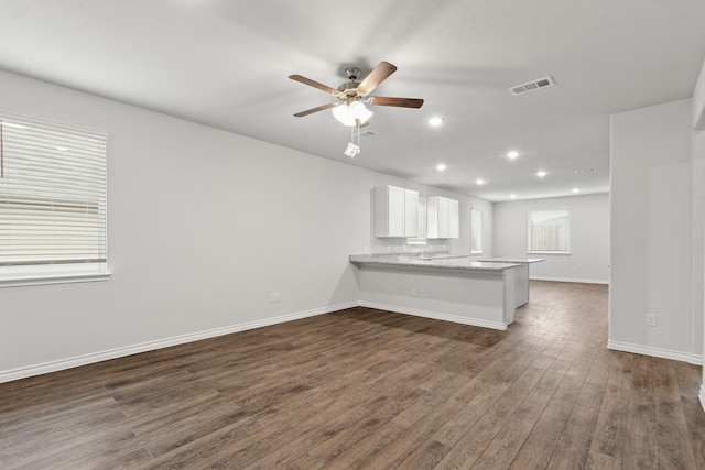 unfurnished living room featuring dark wood-type flooring and ceiling fan